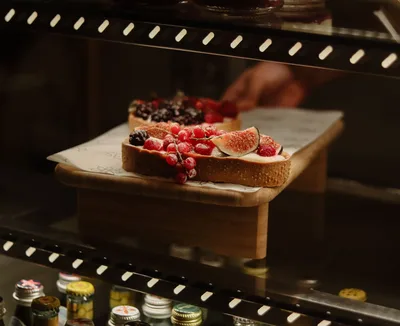 Delicioso pan artesanal cubierto con higos frescos, frambuesas y grosellas en una exhibición de café.